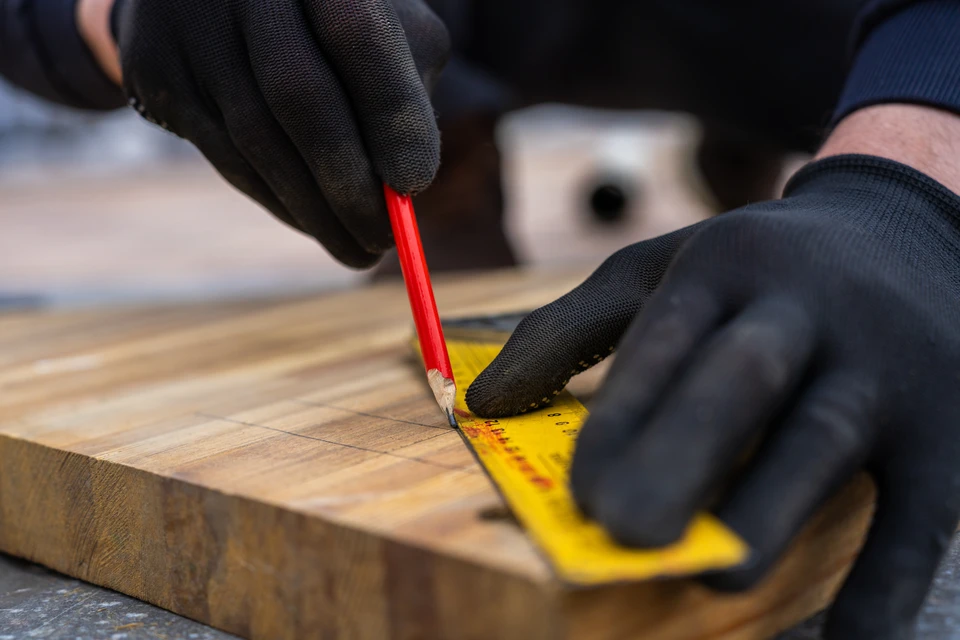 Couvreur en tenue de travail grise posant des tuiles métalliques noires brillantes sur une toiture en cours d'installation