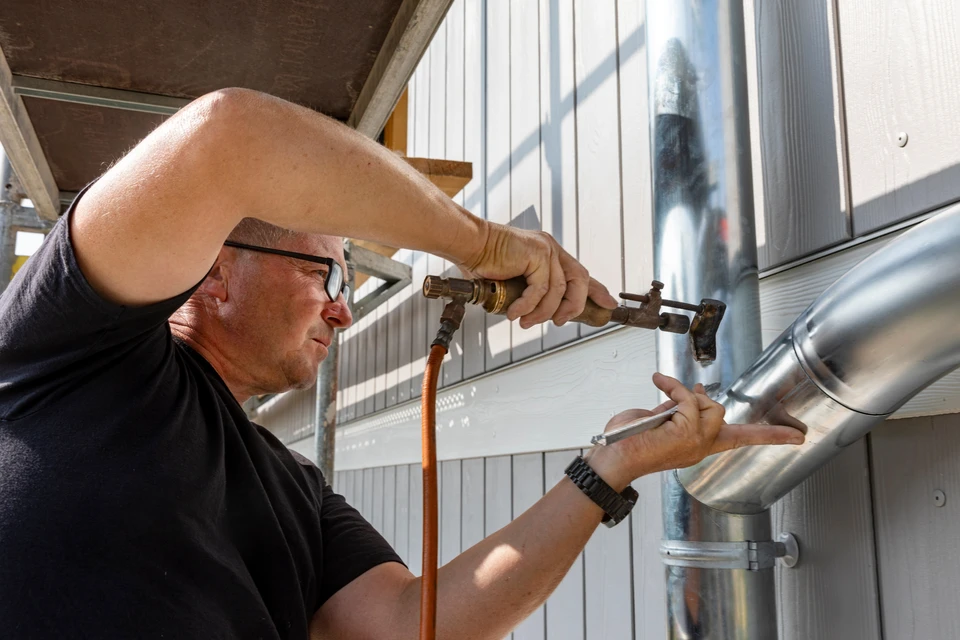 Quatre couvreurs en harnais de sécurité travaillent sur une toiture en cours de réfection